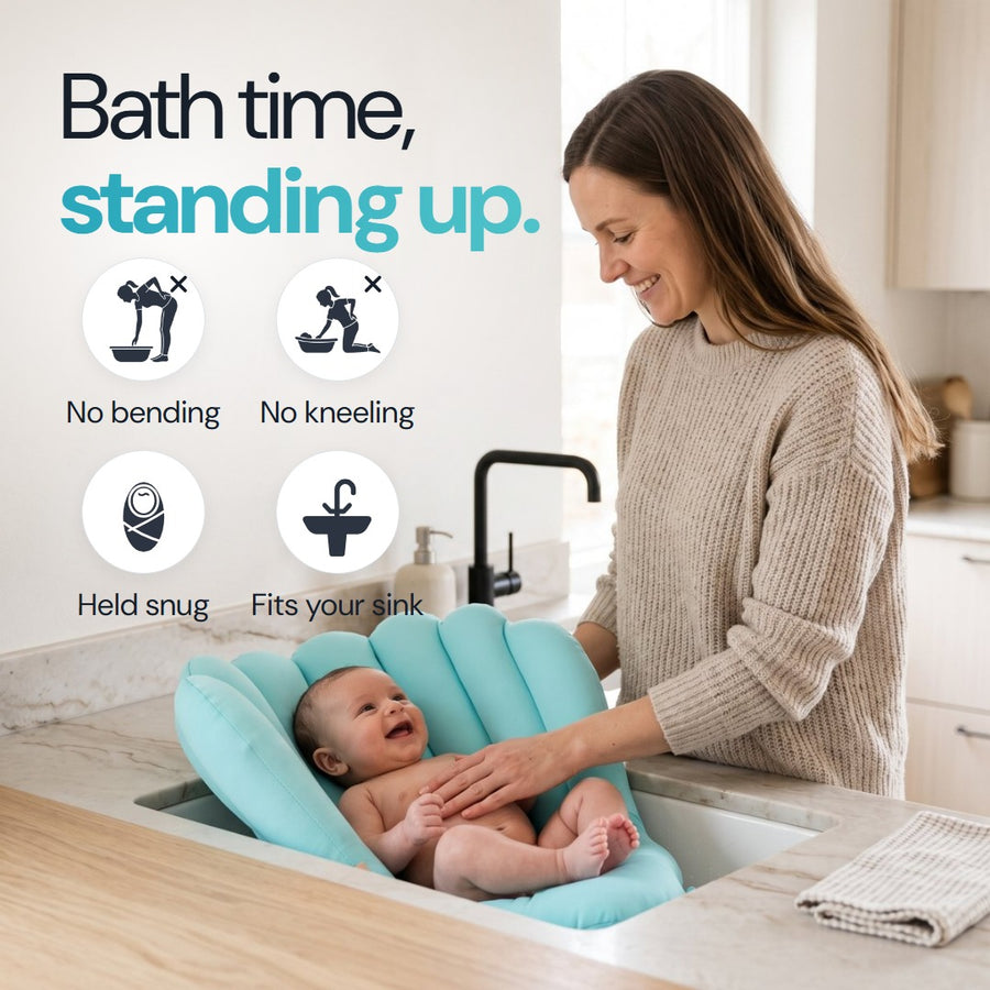 Mum standing at the kitchen sink with her smiling baby in the Sink Bather. Bath time, standing up.