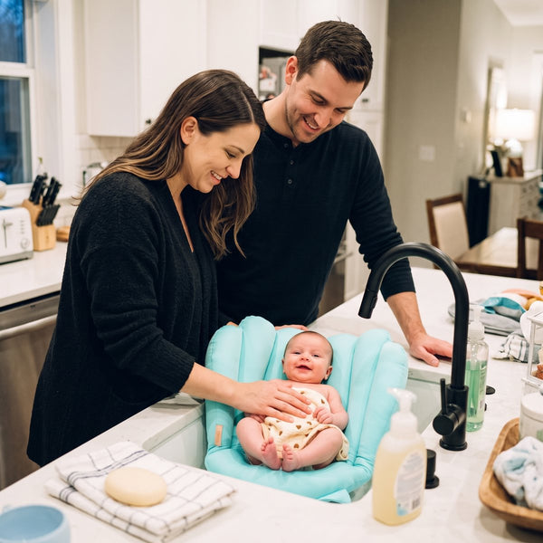 Both parents smiling at their baby at the first bath